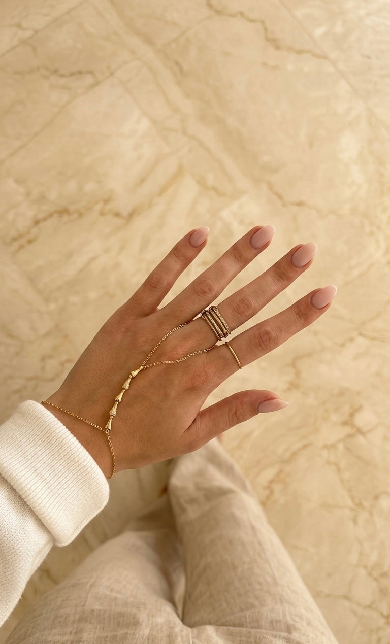 Calla Muse gold hand chain layered with other jewelry